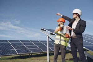 Commercial solar professionals inspecting a ground-mounted solar array at a Hartford, CT business site.